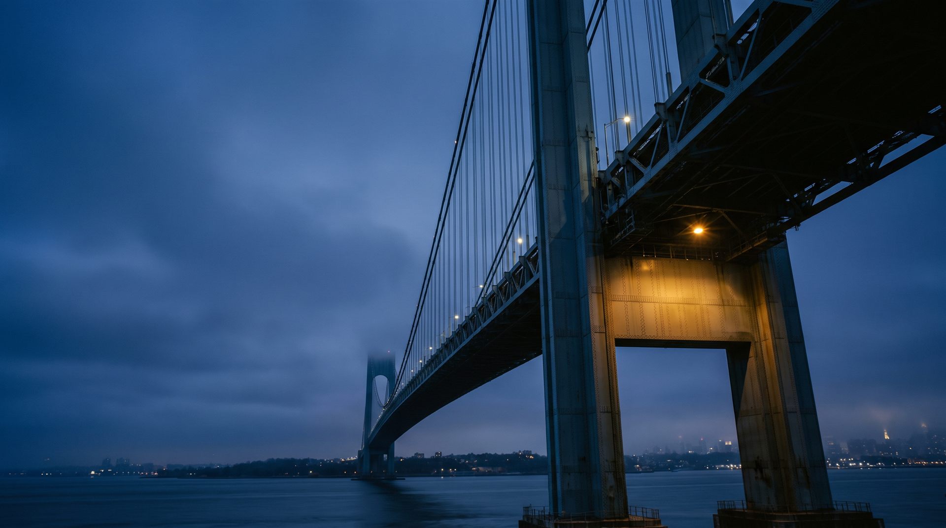 Steel suspension bridge tower and cables photographed at blue hour